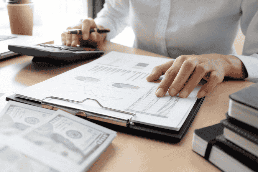 Person reviewing financial statements and charts on a clipboard, analyzing APR vs APY for savings and loan decisions