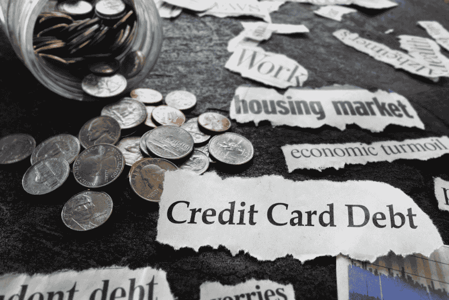 Newspaper clippings with the phrase "Credit Card Debt" surrounded by loose coins
