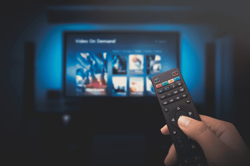 Hand holding a TV remote, representing streaming subscription cancellations and reducing recurring bills