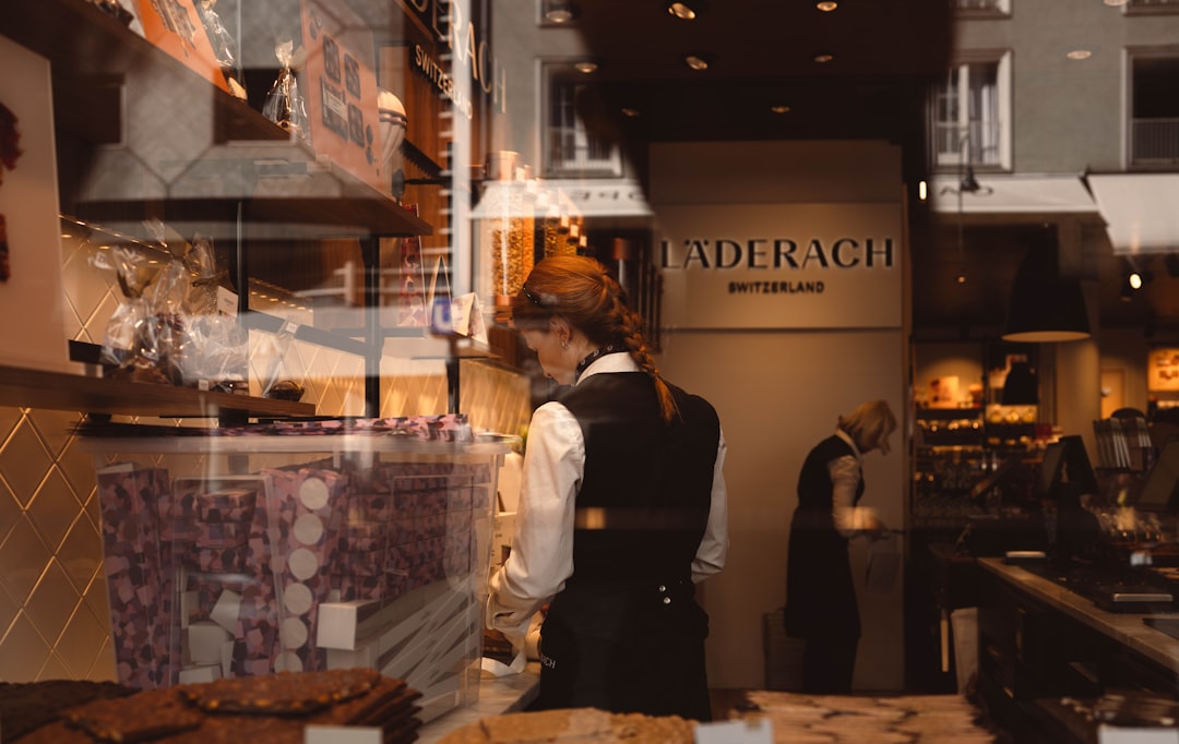 Shopkeeper arranging chocolates in a store window.