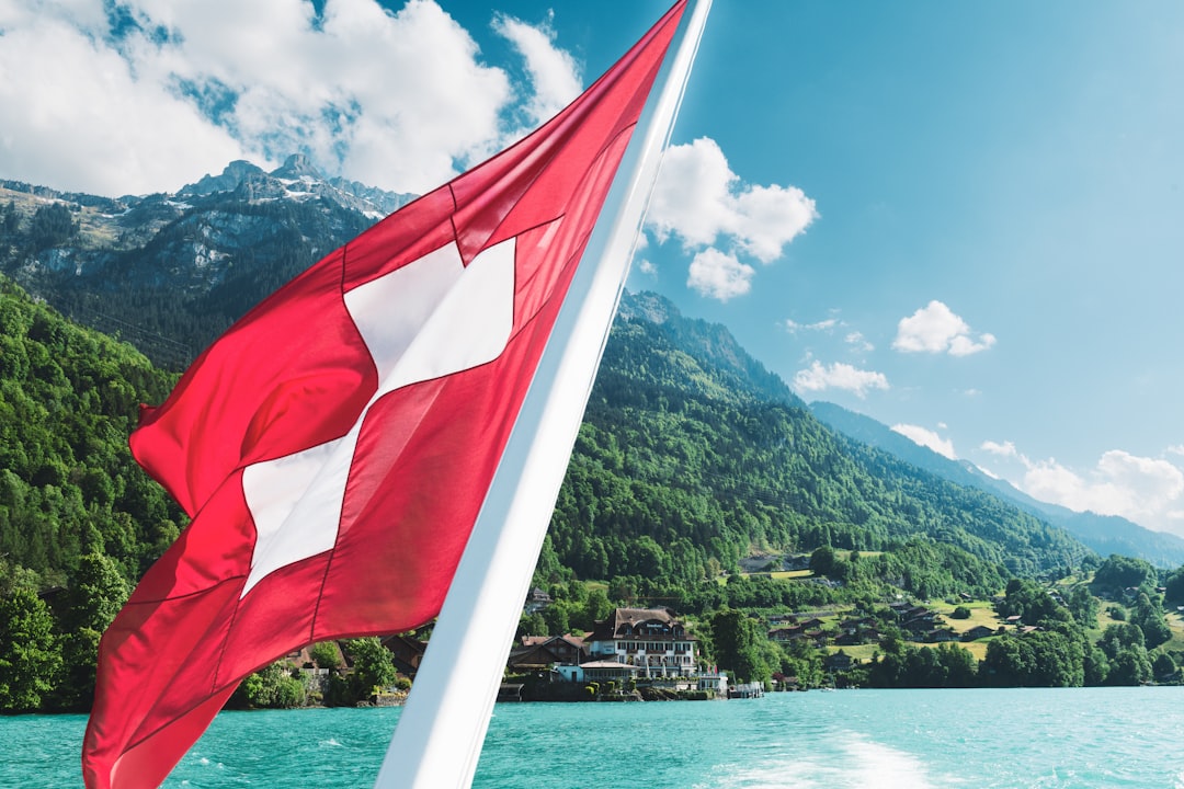 Swiss flag with mountains and water in background.