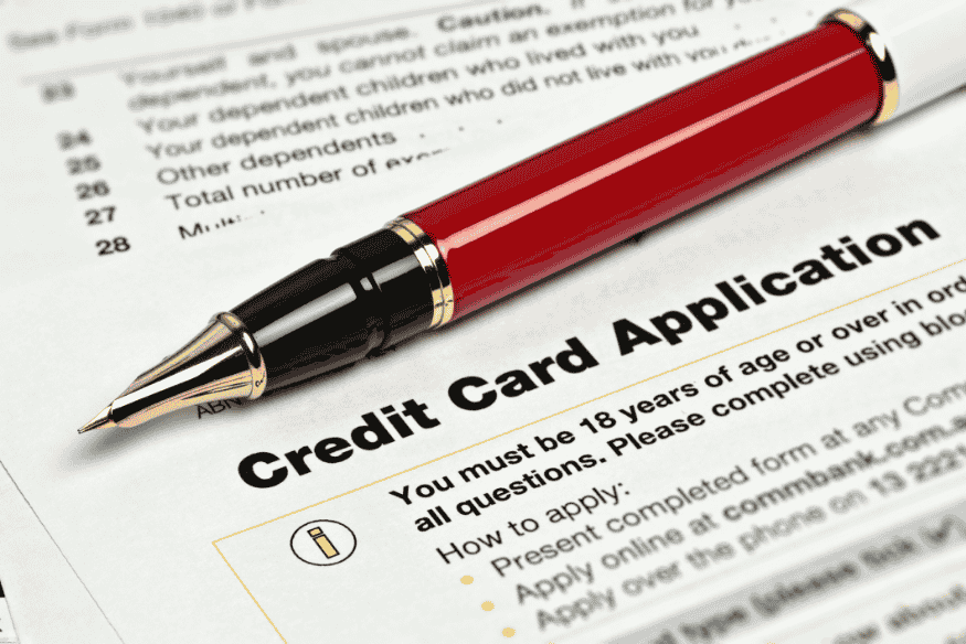 Close-up of a red pen on top of a printed credit card application form