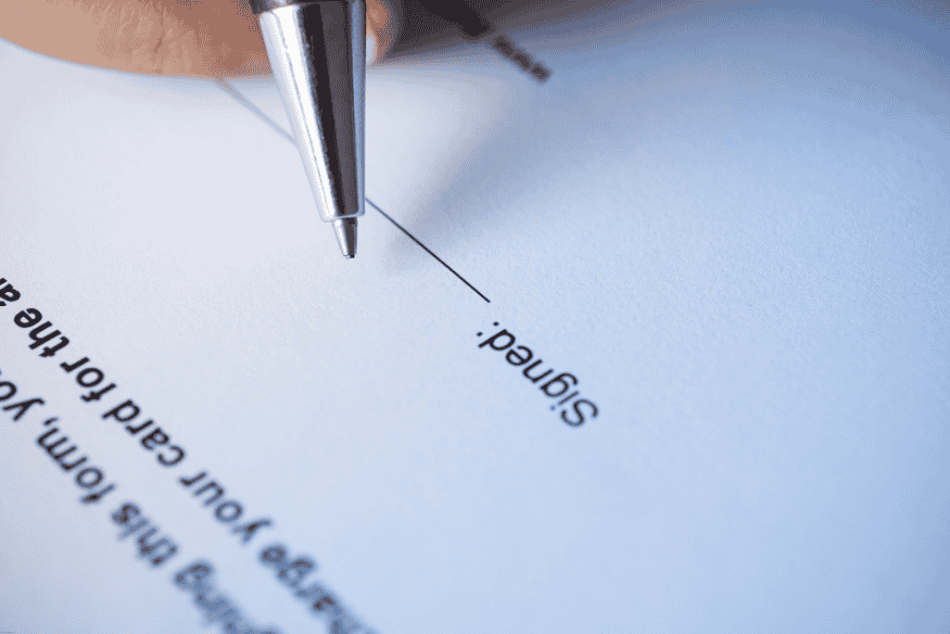 Pen approaching a signature line on a financial document