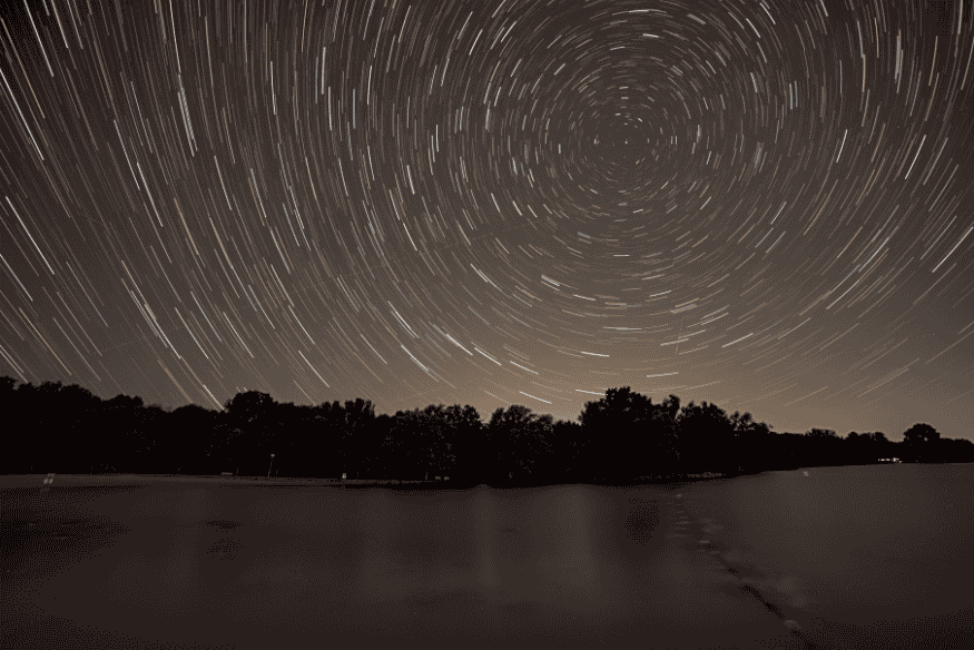 Rastro de estrelas em longa exposição girando ao redor da Estrela Polar no céu noturno.
