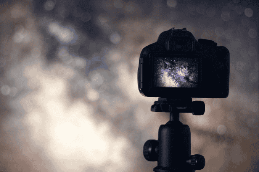 Câmera DSLR em tripé capturando imagem da Via Láctea em longa exposição noturna.