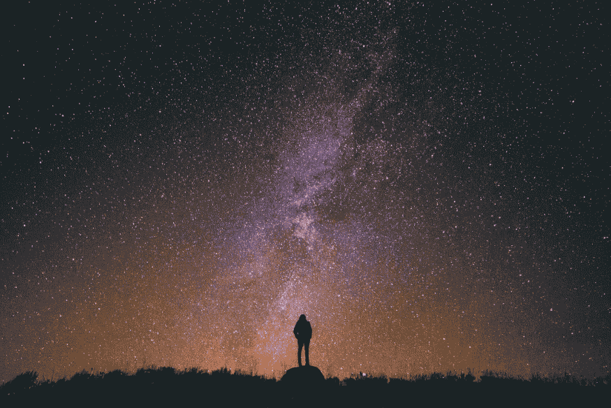 Pessoa observa a Via Láctea em céu escuro, ideal para testes de astrofotografia com celular.
