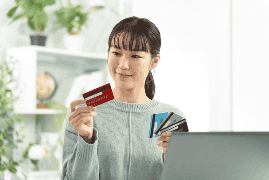 Woman looking at a red credit card while holding others in her hand