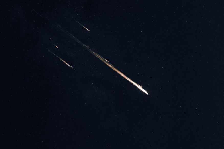 Fragmentos de meteoros cruzando o céu noturno em múltiplas direções.