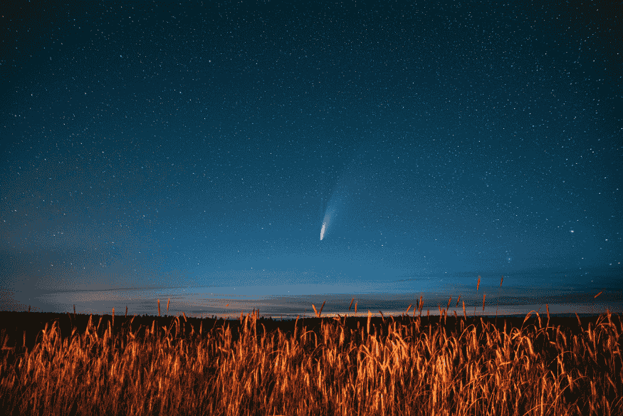 Cometa visível no céu sobre campo ao entardecer
