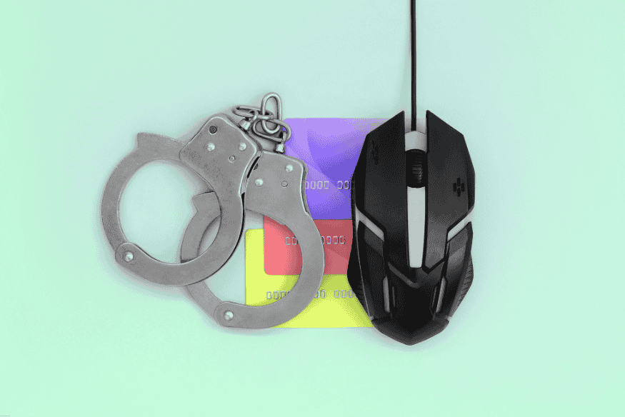 Computer mouse and handcuffs on a credit card symbolizing online credit card fraud.