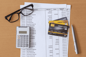 Credit cards, calculator, and bank statements on a desk for financial analysis