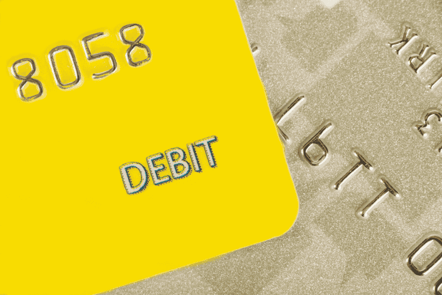 Close-up of a yellow debit card with embossed numbers