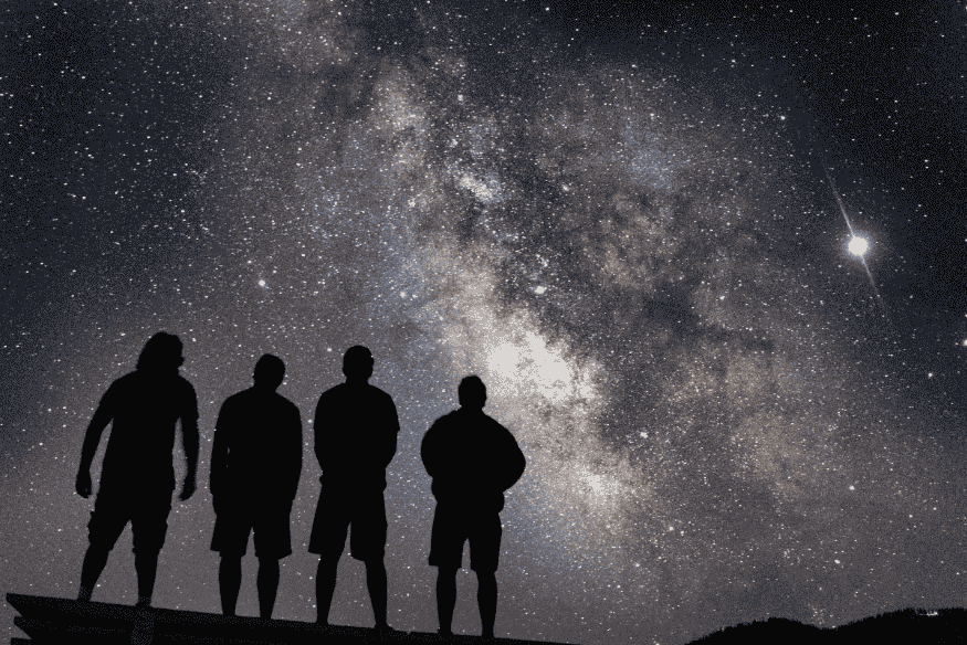 Grupo de pessoas admirando a Via Láctea durante um evento de observação astronômica.