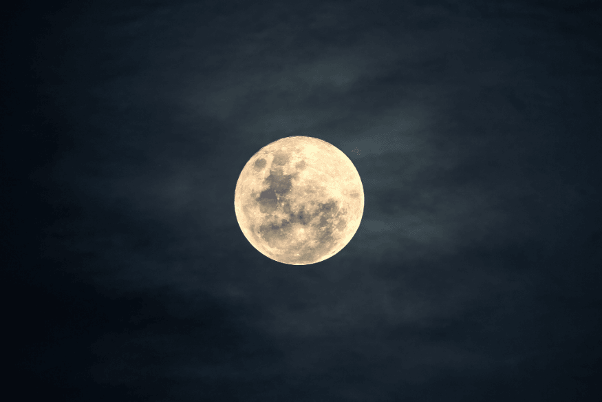 Lua cheia brilhando intensamente no céu noturno com nuvens finas ao redor.