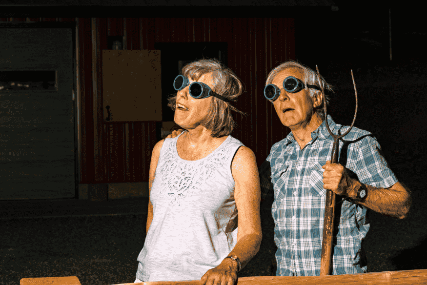 Casal de idosos usando óculos de proteção enquanto observa um eclipse solar.