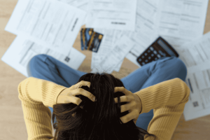 Frustrated woman surrounded by bills, credit cards, and a calculator