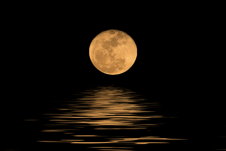 Lua cheia com coloração dourada refletida nas águas calmas, em contraste com o céu noturno.