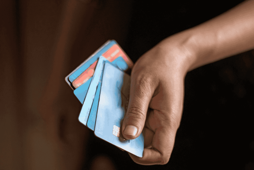 Close-up of a person’s hand holding multiple blue credit cards