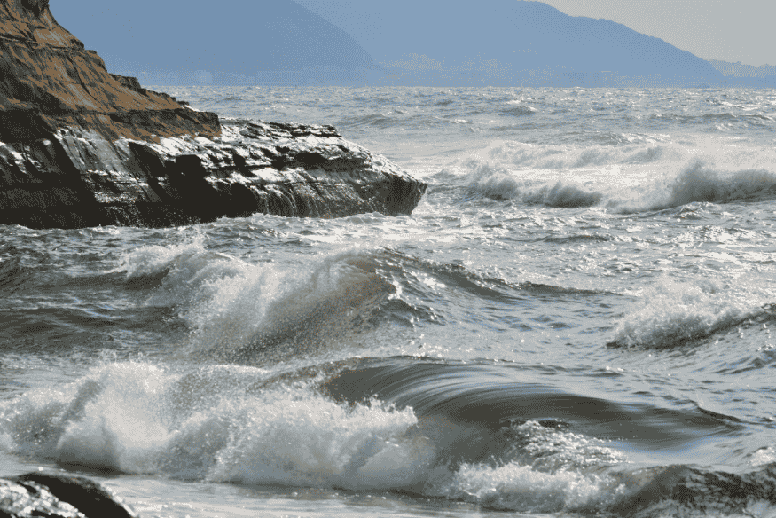 Ondas fortes quebrando em uma costa rochosa durante a maré alta.