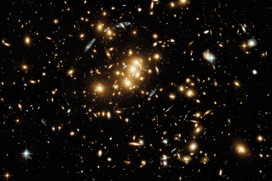 Imagem de aglomerado de galáxias mostrando o efeito de lentes gravitacionais no espaço.