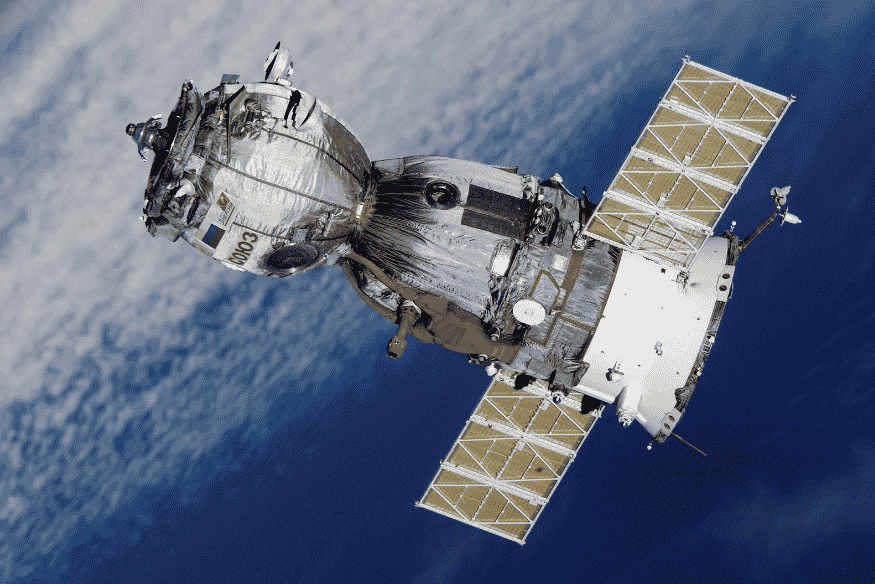 Satélite espacial orbitando a Terra com painéis solares estendidos.