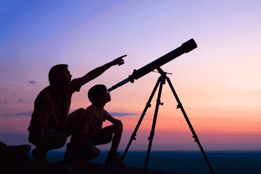 Pessoas observando o céu com um telescópio ao entardecer