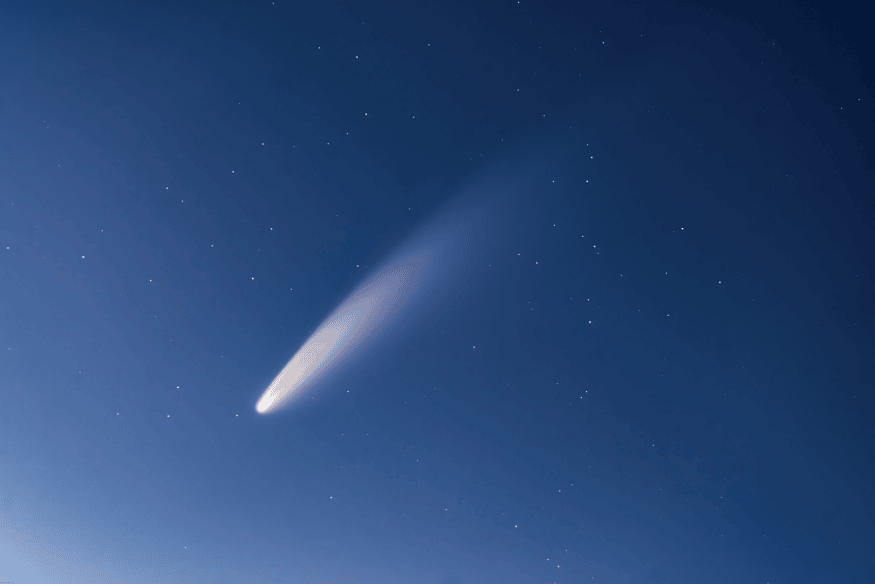 Cometa capturado em preto e branco com detalhes da cauda e núcleo iluminado.