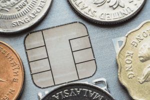 Close-up of a credit card chip surrounded by international coins