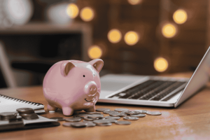 Piggy bank with coins beside a laptop, representing automatic savings and simple money habits