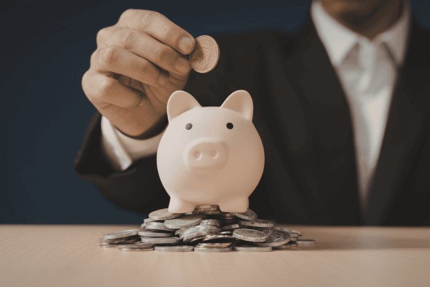 Person adding a coin to a piggy bank, symbolizing automatic savings and consistent saving habits