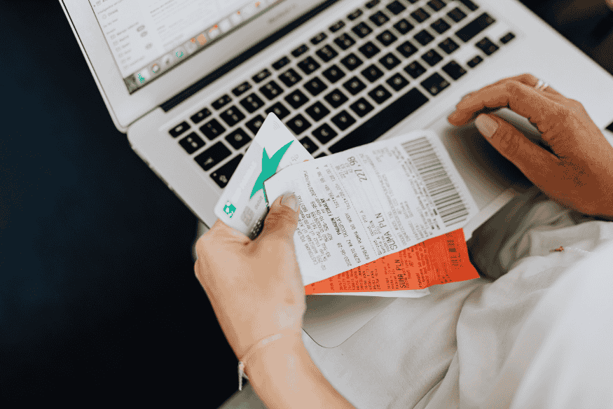 Person holding a credit card and receipts over a laptop, tracking spending during a balance transfer period